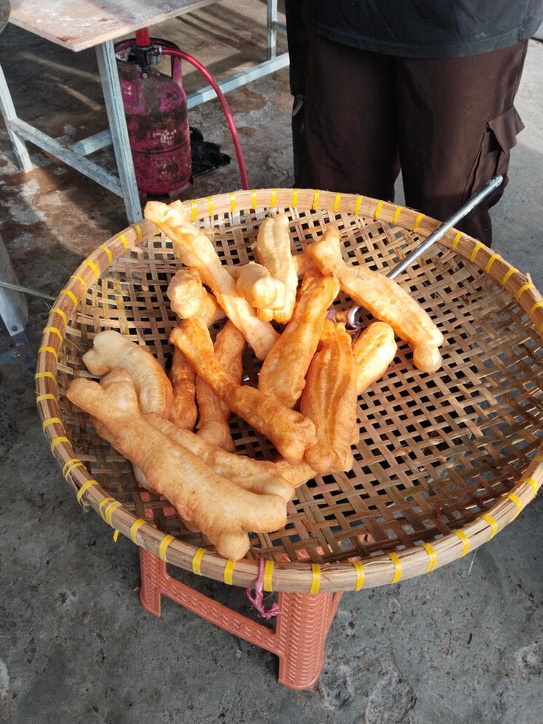 foto: seorang pedagang kue cakwe saat mengangkat kue dari pengglorengan